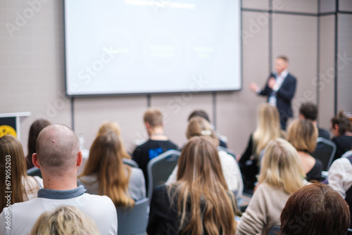 Back view of businesswoman attending presentation with diverse participants in conference hall  © Anton Gvozdikov