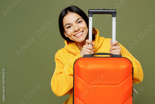 Traveler happy Latin woman wear yellow hoody casual clothes hold bag isolated on plain pastel green background. Tourist travel abroad in free spare time rest getaway. Air flight trip journey concept.