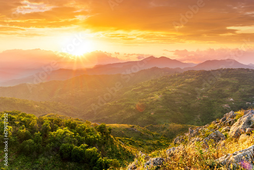 highland mountain landscape of beautiful sunset or sunrise with nice mountain peaks and slopes, green and golden hills and majestic cloudy sky on background © Yaroslav