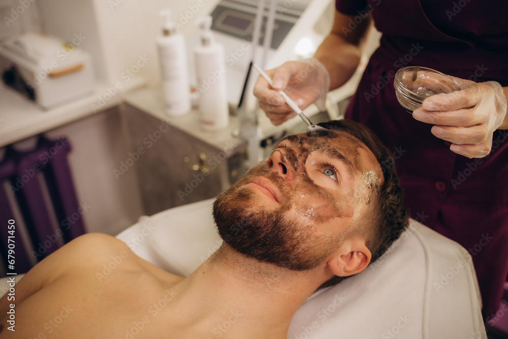 Cosmetologist applying mask on client's face in spa salon Cosmetologist applying mask on client's face in spa salon