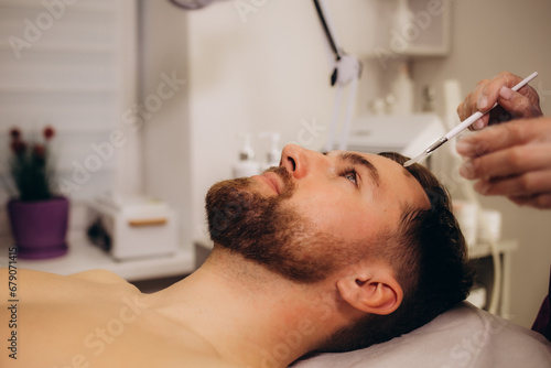 a beautician performs fractional mesotherapy on a man