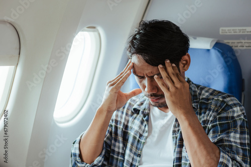 headache on airplane Male passenger is afraid and feels bad while flying on an airplane.