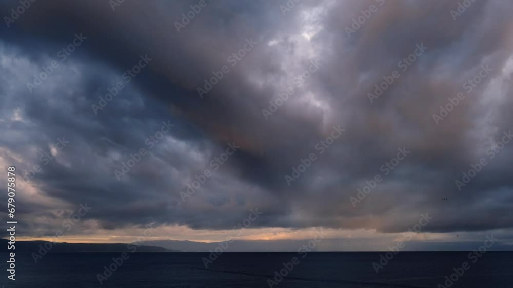 Fast motion dramatic sunrise at the beach. Dark tropical storm clouds with colourful lights moving against the sky. Magnificent nature landscape. First rays of the sun above the sea on a windy morning Fast motion dramatic sunrise at the beach. Dark tropical storm clouds with colourful lights moving against the sky. Magnificent nature landscape. First rays of the sun above the sea on a windy morning