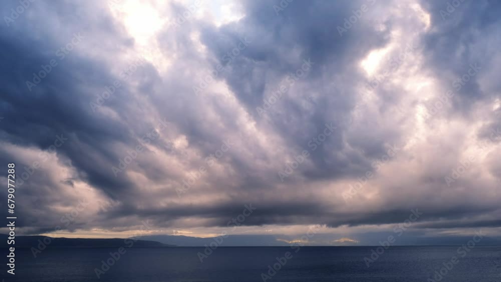 Real time dramatic sunrise at the beach. Dark tropical storm clouds with colourful lights moving against the sky. Magnificent nature landscape. First rays of the sun above the sea on a windy morning. Real time dramatic sunrise at the beach. Dark tropical storm clouds with colourful lights moving against the sky. Magnificent nature landscape. First rays of the sun above the sea on a windy morning.