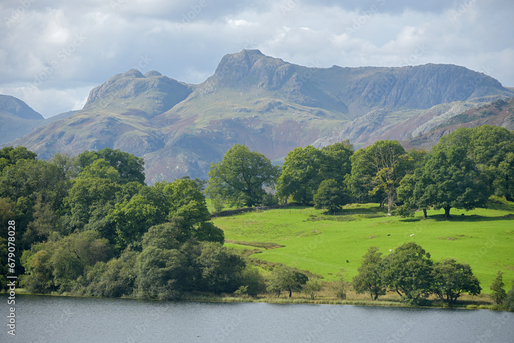 The small lake of Loughrigg Tarn beneath the Langdale Pikes in the Lake District