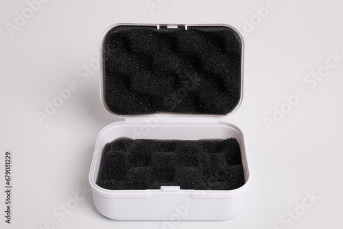 White open box lined with black sponge inside, isolated on a white background. Black mini pouch bag for storing small things. Inside of the protection bag