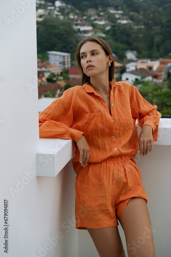 Pretty brunette woman in summer linen costume posing outdoor oer white eall. Trendy summer outfit. White top. Fashion photo. photo