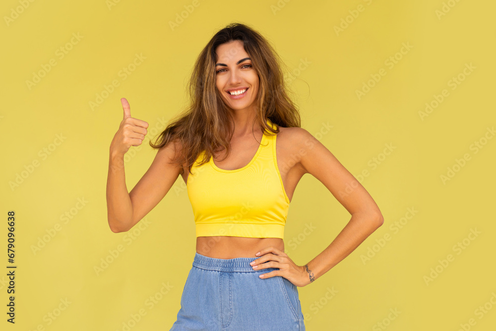 Studio photo of pretty brunette woman in sportive outfit posing on yellow background. Studio photo of pretty brunette woman in sportive outfit posing on yellow background.