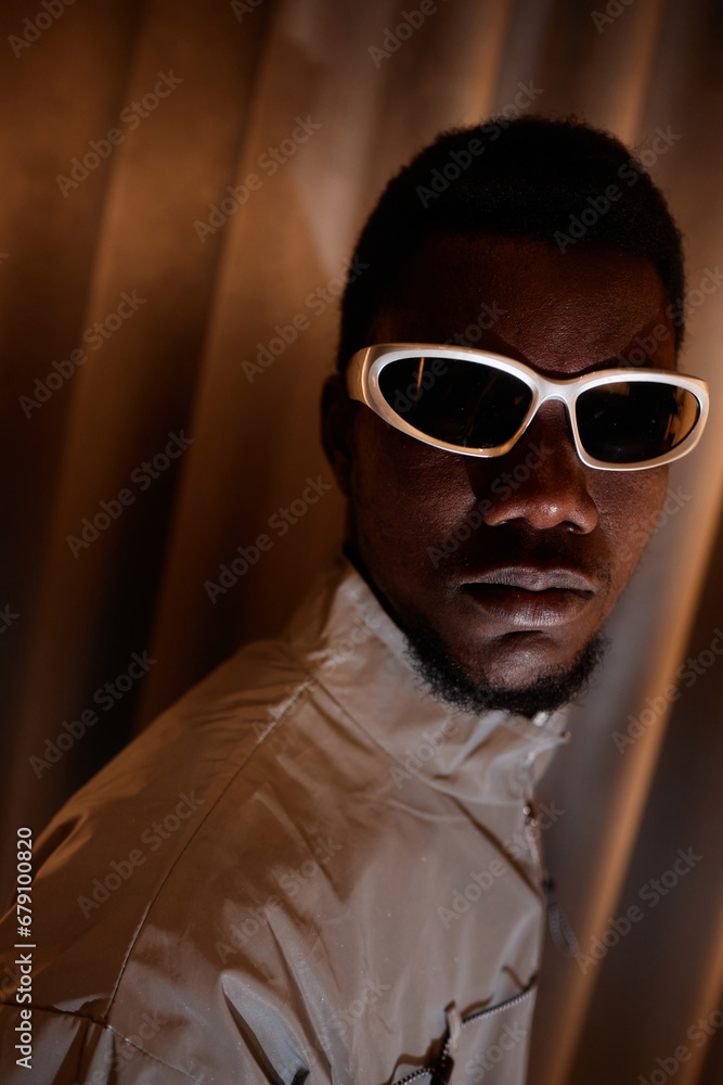 Obraz premium Close up fashion portrait of young Black man wearing 90s style sunglasses and looking at camera intensely