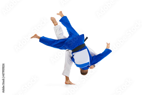 Two male professional sportsmen during match. Judo fighter attacking his opponent with leg technique isolated white background. photo