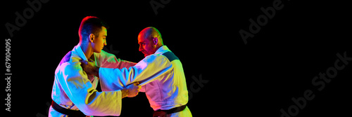 Banner. Portrait of two man looking eyes to eye while fighting in neon light isolated black background with negative space to insert your text. photo