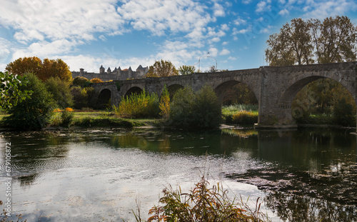 The old bridge and in the background the city of Carcassonne, and the Aude river, in Aude, in Occitanie, France.