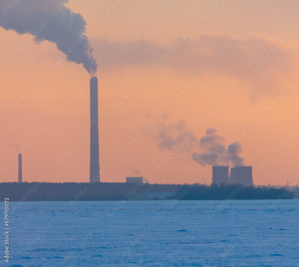 Smoke from the chimneys of an industrial plant at sunset in winter