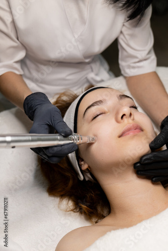 Fractional mesotherapy. A young beautiful woman in the cosmetologist’s office receives fractional mesotherapy for her face. Facial skin rejuvenation. Acne treatment. Hardware cosmetology. Beautician. 