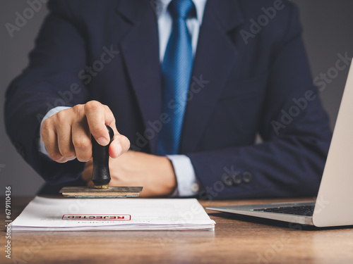 Businessman stamped for rejected documents while sitting at the table.