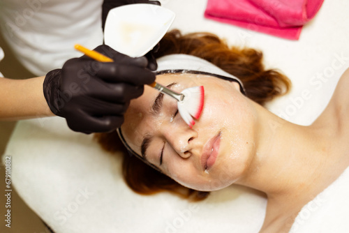 A cosmetologist applies anti-aging face masks. model girl lies with her eyes closed. Healthy skin. High quality photo