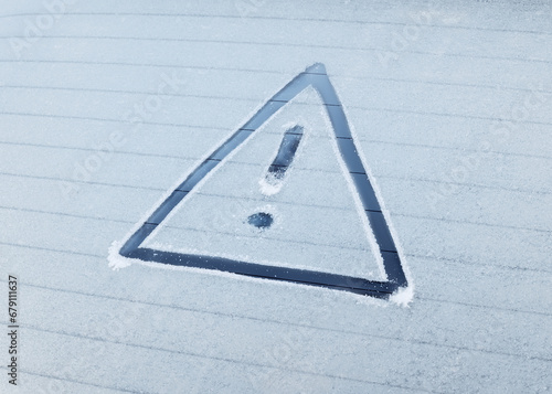 Winter Driving - Caution! - A warning triangle drawn in the ice on a frozen rear window of a car