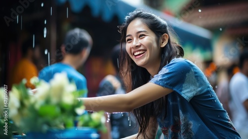 A happy smiling woman brushes her cheeks wearing a blue floral shirt. and pointing the finger at the empty space during the Songkran festival © somchai20162516