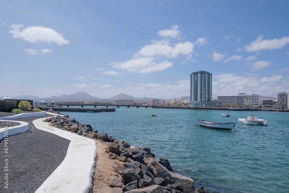 Fototapeta premium View of the city of Arrecife from the Fermina islet. Turquoise blue water. Sky with big white clouds. Seascape. Lanzarote, Canary Islands, Spain.