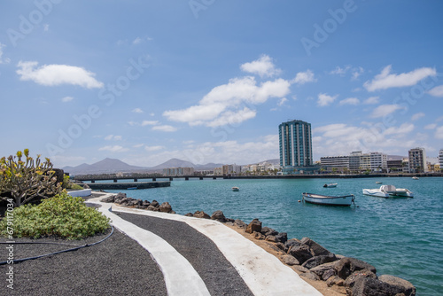 Fototapeta Naklejka Na Ścianę i Meble -  View of the city of Arrecife from the Fermina islet. Turquoise blue water. Sky with big white clouds. Seascape. Lanzarote, Canary Islands, Spain.