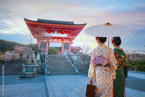 Young Japanese women in a traditional Kimono dress stroll in Kiyomizu-dera Buddhist temple in Kyoto, Japan during full bloom cherry blossom in spring