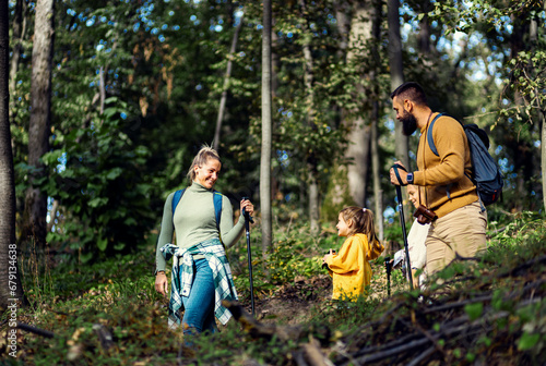 Smiling family of four enjoying hiking in trough forest.