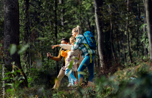 Smiling family of four enjoying hiking in trough forest.