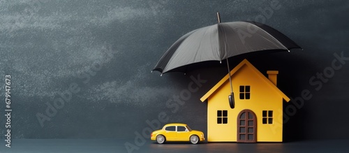 Insurance protects properties like cars and homes depicted as paper cutouts under a yellow umbrella on a blackboard background Copy space image Place for adding text or design photo