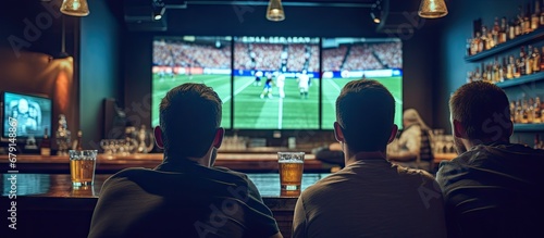 Friends in sports bar watching game on screens from behind Copy space image Place for adding text or design photo