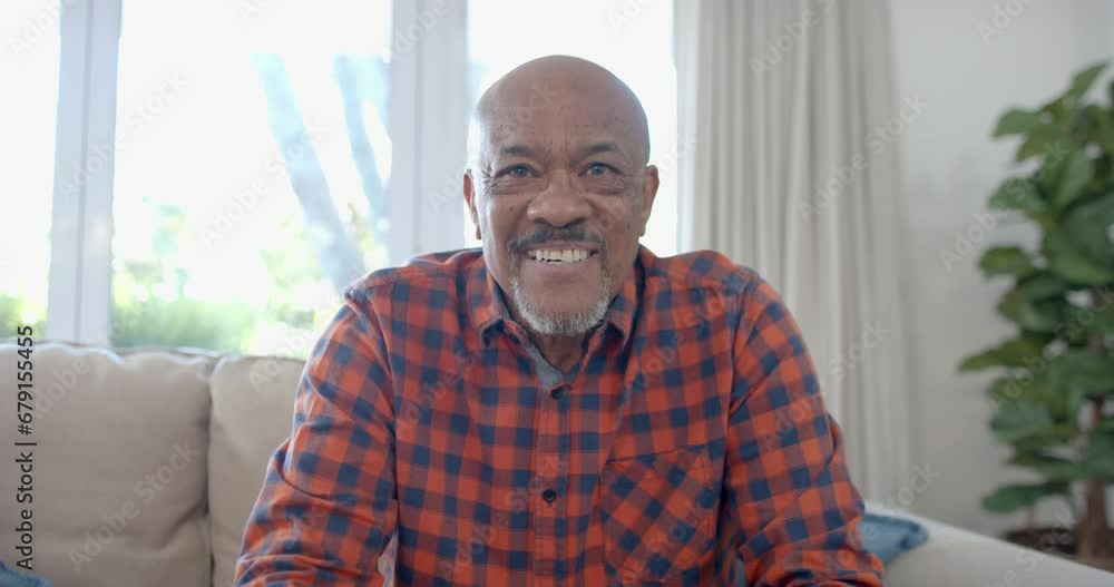 Portrait of happy senior biracial man sitting on couch having video call at home, slow motion Portrait of happy senior biracial man sitting on couch having video call at home, slow motion