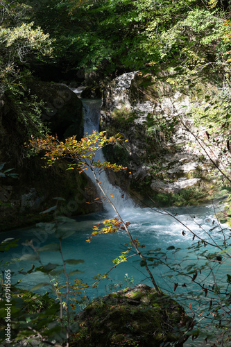 Paisaje otoñal de una cascada en el nacedero del río Urederra en la sierra de Urbasa con hayas y el agua del río, Navarra, España.
