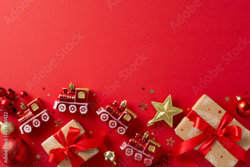 ‘Tis the season to decorate. Overhead shot of charming gift boxes wrapped in craft paper, adorned with red and gold baubles, creative Christmas tree toys, confetti, on vibrant red backdrop for text photo