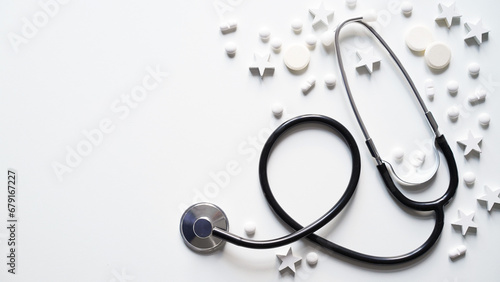 Christmas medical banner. Close-up of stethoscope, stars and pills on white background, top view, flat lay, copy space. New Year's medicine, congratulations to doctor.