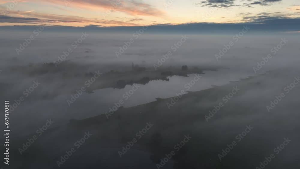 Ijssel river covered in a blanket of mist seen from above during a fall morning in Overijssel. The fog surrounding the river is giving the landscape a mystical atmosphere. Ijssel river covered in a blanket of mist seen from above during a fall morning in Overijssel. The fog surrounding the river is giving the landscape a mystical atmosphere.