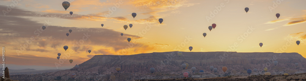 A panorama of hot air balloons in the sky at dawn against the backdrop of mountains. Breathtaking colors fill the sky. A panorama of hot air balloons in the sky at dawn against the backdrop of mountains. Breathtaking colors fill the sky.