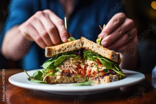 person devouring a tuna salad sandwich in a bistro photo