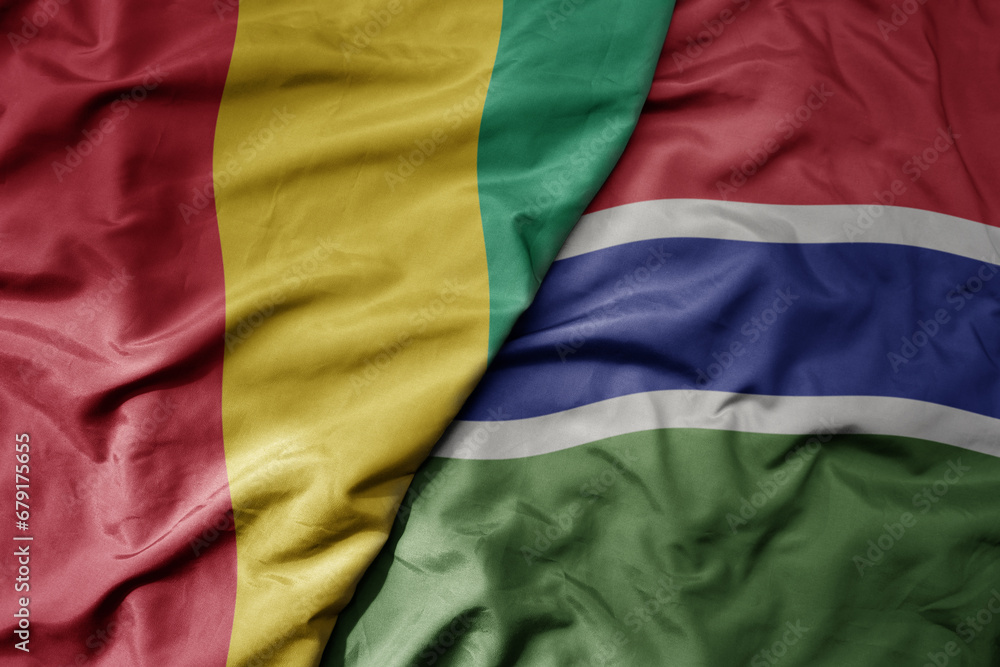 Obraz premium big waving national colorful flag of guinea and national flag of gambia .