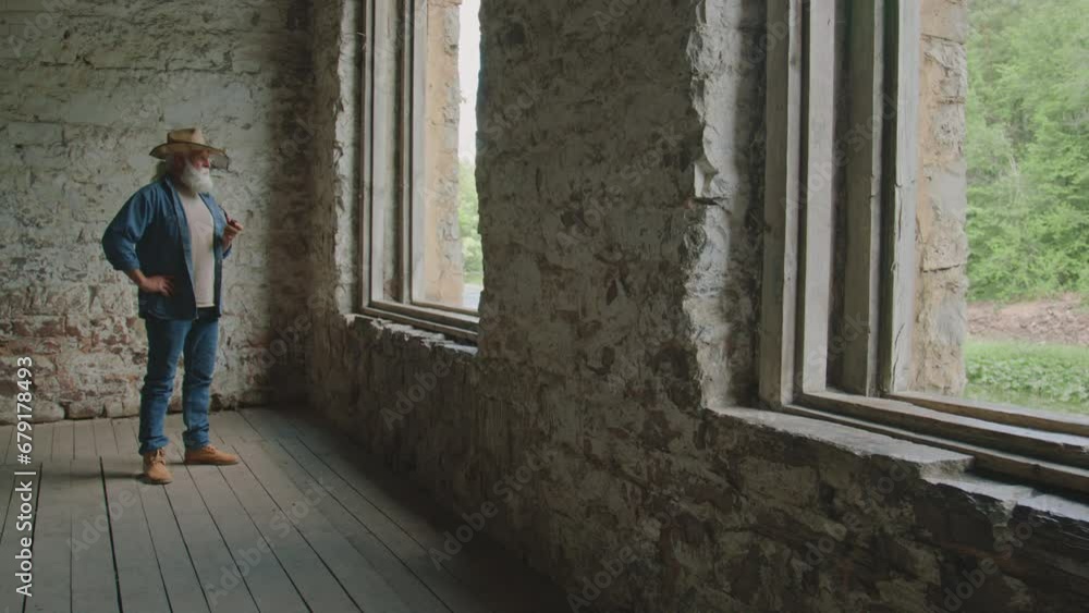 Very long shot of senior handyman standing inside unfinished house and smoking pipe Very long shot of senior handyman standing inside unfinished house and smoking pipe