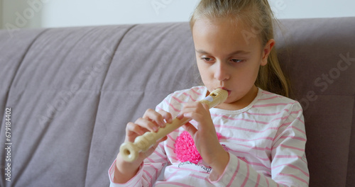 Little girl practice playing the flute at home