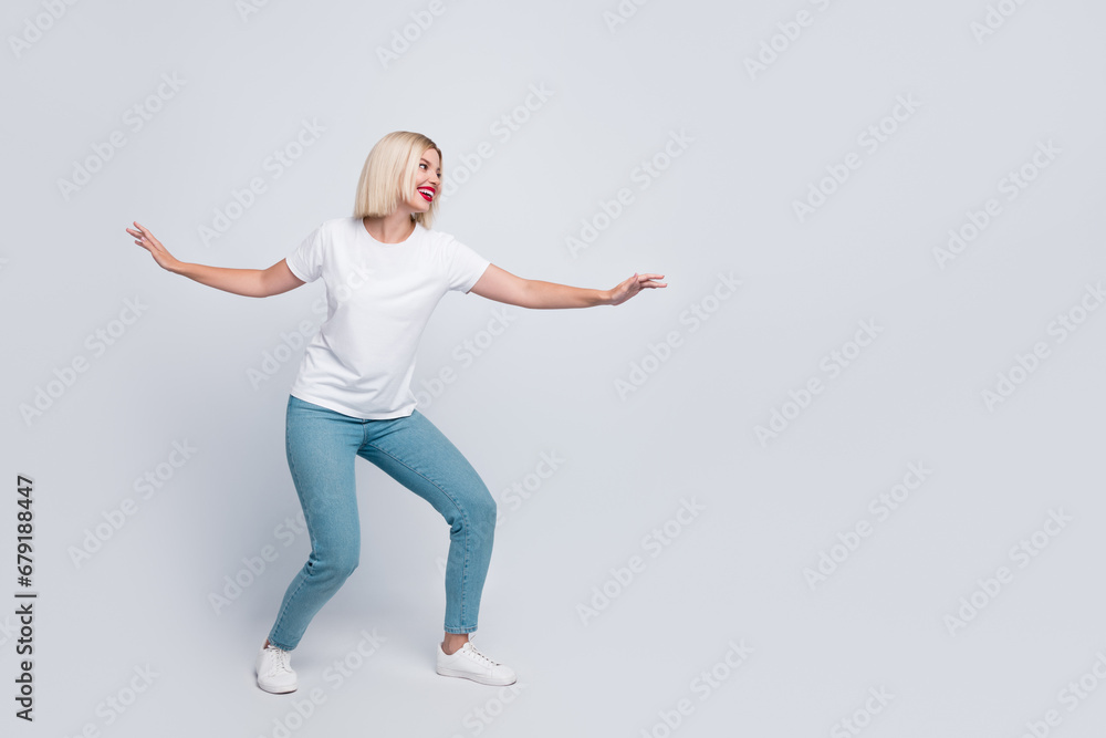 Full body photo of adorable positive nice woman wear stylish t-shirt look at proposition empty space isolated on gray color background