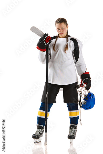 Young girl, hockey player in uniform standing with stick and posing isolated over white background. Champion. Concept of professional sport, competition, game, action, hobby