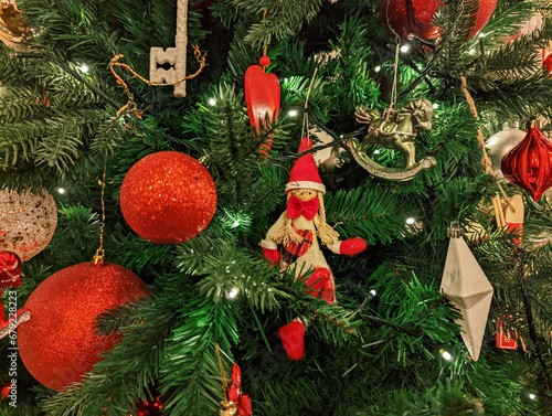 Red toy balloons are hanging on the Christmas tree. close-up