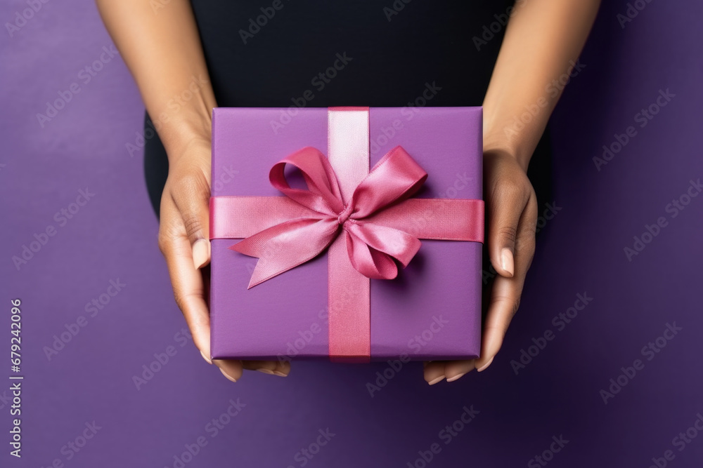Women's hands holding purple gift box with ribbon. Women's hands holding purple gift box with ribbon.