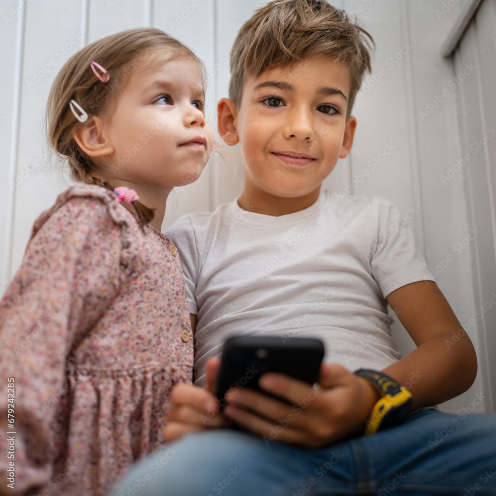 Boy and girl brother and sister use mobile phone smartphone at home Boy and girl brother and sister use mobile phone smartphone at home