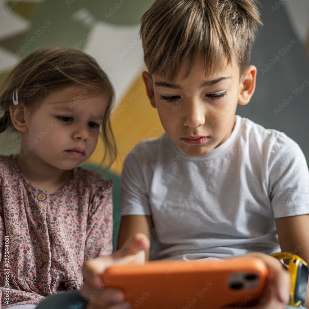 Boy and girl brother and sister use mobile phone smartphone at home Boy and girl brother and sister use mobile phone smartphone at home