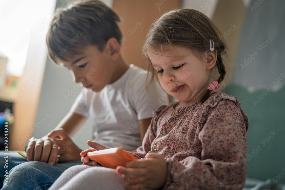 Boy and girl brother and sister use mobile phone smartphone at home Boy and girl brother and sister use mobile phone smartphone at home