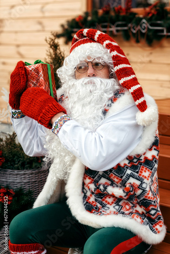 Saint Nicholas in festive decoration against the background of a wooden house photo