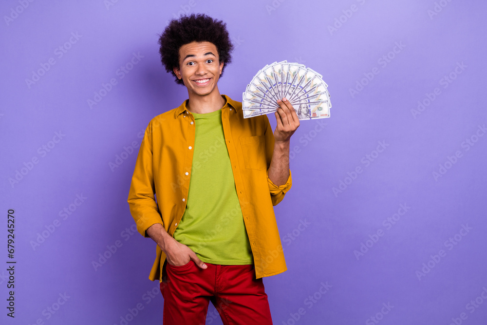 Photo of positive nice man wear trendy clothes hand showing banknotes million dollars isolated on violet color background Photo of positive nice man wear trendy clothes hand showing banknotes million dollars isolated on violet color background