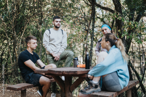 Young friends hike through an autumn forest, enjoying fresh air and fun conversations. Dressed in sportswear, they embrace outdoor adventure and healthy recreation in natures wilderness.