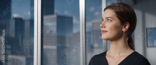 Free Download Close Up Beautiful Portrait of Caucasian Businesswoman Posing Next to Window in Big City Office with Skyscrapers. Female CEO Smiling, Looking At Camera. Successful Business Manager. - GFXLoad